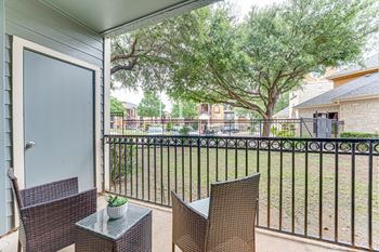 A patio with a table and chairs overlooking a fence.